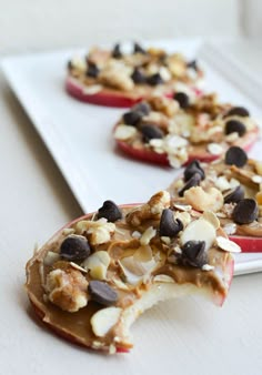 apple halves with chocolate chips and nuts on them sitting on a white plate, ready to be eaten