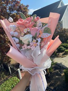 a bouquet of flowers is being held by someone's hand in front of a house