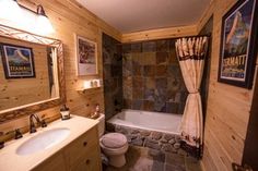 a bathroom with stone walls and tile flooring, along with a bathtub in the corner