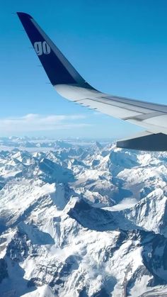 the wing of an airplane flying over snow covered mountains