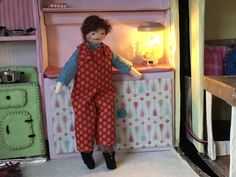 a doll is standing in front of a toy refrigerator with its door open and lights on