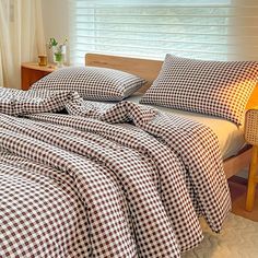 a bed with checkered sheets and pillows in a bedroom next to a lamp on a nightstand