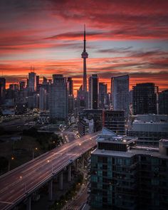 the city skyline is lit up at night with red and orange clouds in the sky