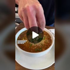 a person is dipping something into a bowl of soup