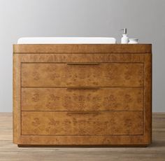 a wooden dresser sitting on top of a hard wood floor next to a white sink