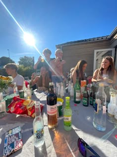 a group of people sitting around a table with bottles and glasses on top of it