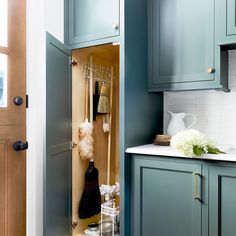 an open cabinet in a kitchen with blue cabinets and white counter tops, filled with utensils