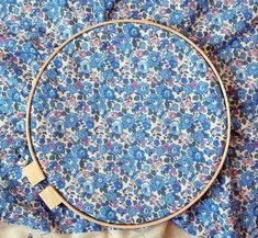 a close up of a flowered cloth with a cross stitch hoop on top of it