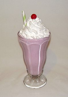 a purple glass with whipped cream and a cherry on top