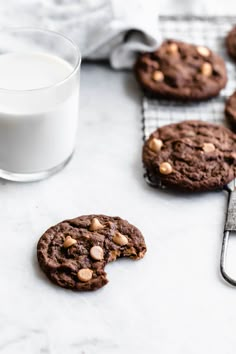 chocolate cookies and milk on a cooling rack next to a glass of milk with spoons