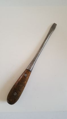 an old wooden spoon sitting on top of a white wall next to a knife blade