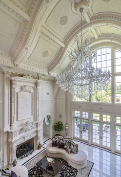 an ornate living room with chandelier, couch and large window in the center