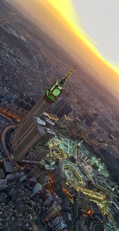 an aerial view of a city at night with the sun setting in the sky and buildings lit up