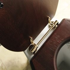 a wooden toilet seat with brass hardware on the lid and back panel, in a bathroom