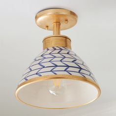 a white and blue light fixture with a gold finish on the top, hanging from a ceiling