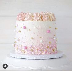 a white cake with pink frosting and gold sprinkles on it's side