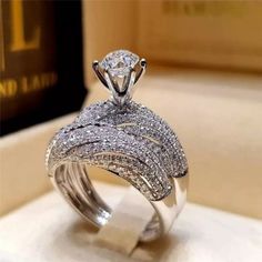 a white gold ring with diamonds on it and a book in the back ground behind it