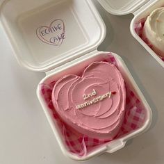 three plastic containers filled with pink frosting and heart shaped cupcakes on top of a table