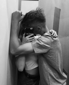 two people hugging each other in front of a mirror