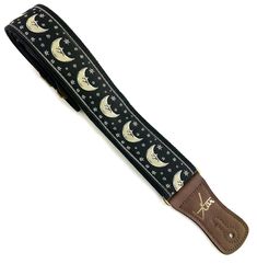 the moon and stars guitar strap is black with brown leather straps, which are decorated with white stars and crescents