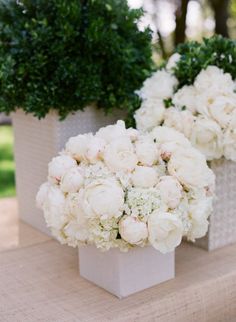 two white vases filled with flowers on top of a table