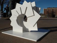 a white sculpture sitting on top of a cement slab