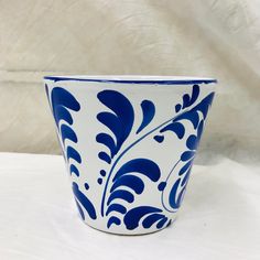 a blue and white flower pot sitting on top of a white table next to a wall