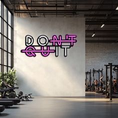 a neon sign that says don't quit in front of a gym with rows of exercise equipment