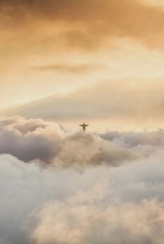 an airplane flying above the clouds at sunset