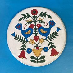 a white plate with blue and red birds on it's side against a blue background