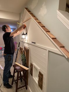 a man is painting the side of a house with white paint and wood trimming