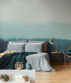 a bedroom with blue walls and wooden floors is pictured in this image, the bed has two pillows on it