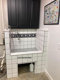 a dog washroom with black cabinets and white tile flooring that has the words doggwashing written on it