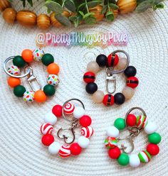 four pairs of colorful beaded earrings sitting on top of a white table next to green leaves