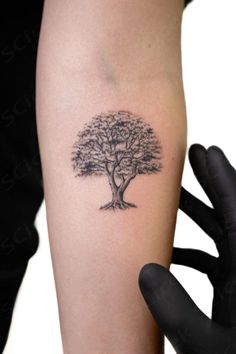 a tree tattoo on the left arm and right hand with black ink in front of it