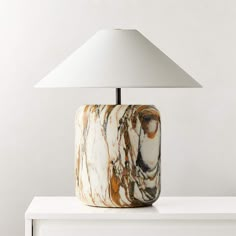 a lamp that is sitting on top of a white shelf next to a table with a marbled surface