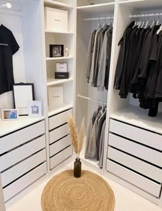 a white closet filled with lots of clothes and drawers next to a rug on the floor