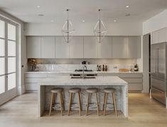 a kitchen with marble counter tops and stools next to an island in the middle