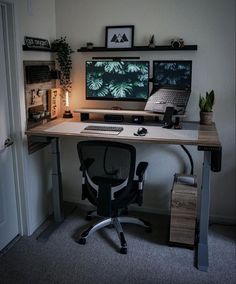 a computer desk with two monitors and a keyboard on it in front of a door