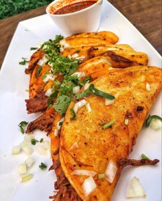 some food on a white plate with sauce and garnishes next to it