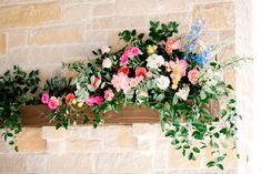 flowers and greenery are growing on the ledge of a brick wall in front of a fireplace