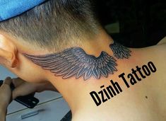 the back of a man's neck with an angel wing tattoo on his left side