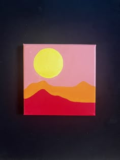 a painting on a black surface with a yellow sun in the sky and mountains behind it