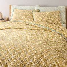 a bed with yellow and white bedspread in a bedroom next to a night stand