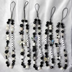 several black and white beaded necklaces with name tags on them hanging from strings