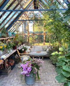 a greenhouse filled with lots of plants and flowers next to a bed in the middle