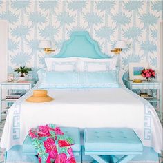 a blue and white bedroom with pink flowers on the nightstands next to the bed