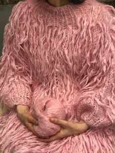 a woman in a pink fuzzy sweater holding her stomach