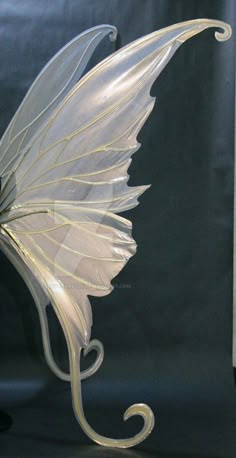 a glass figurine with a white flower on it's head and wings