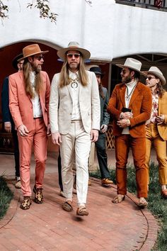 three men in suits and hats are walking down the sidewalk with one man wearing an orange suit